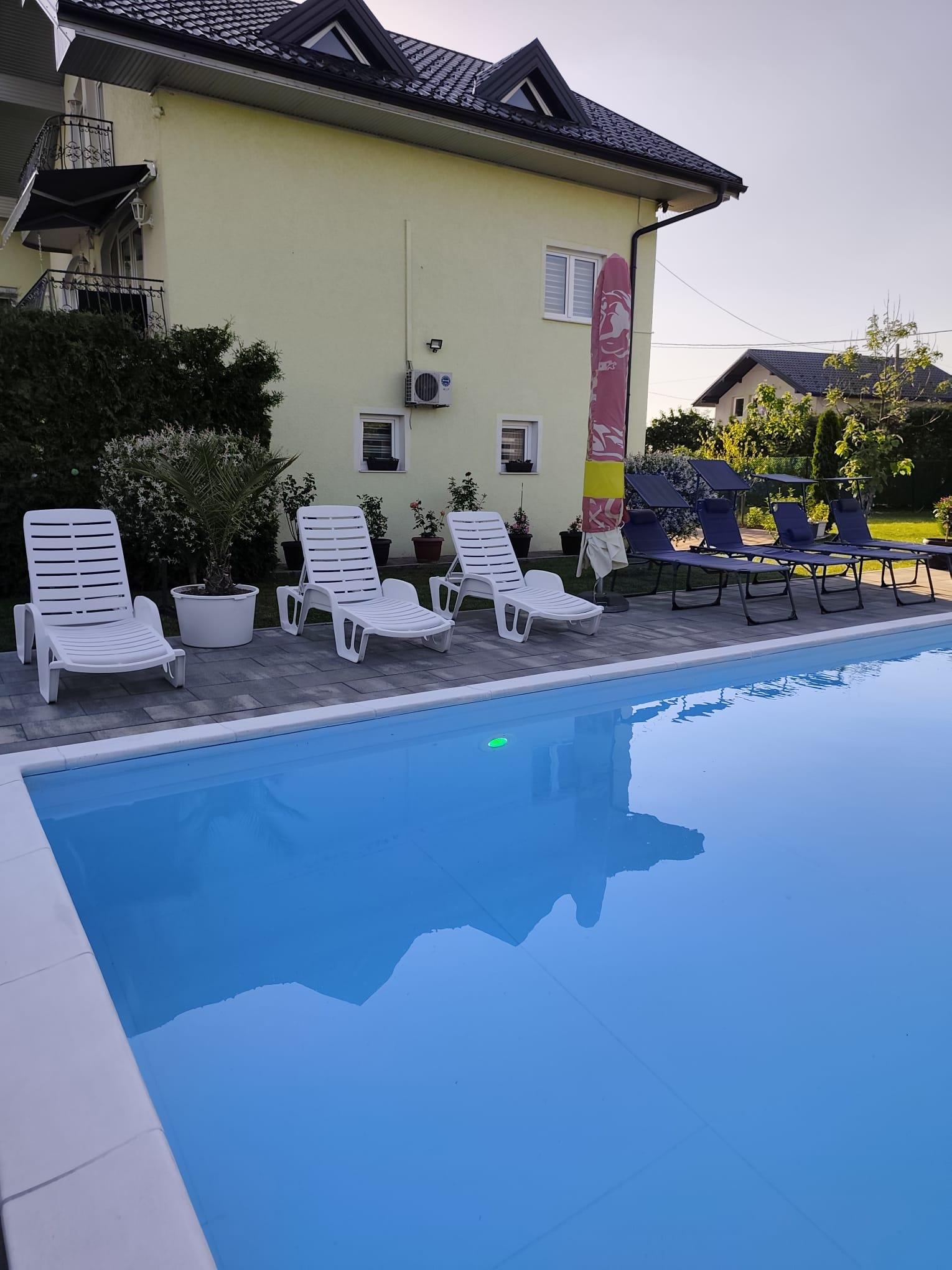 Ležaljke uz bazen pored svijetložute fasade vile.