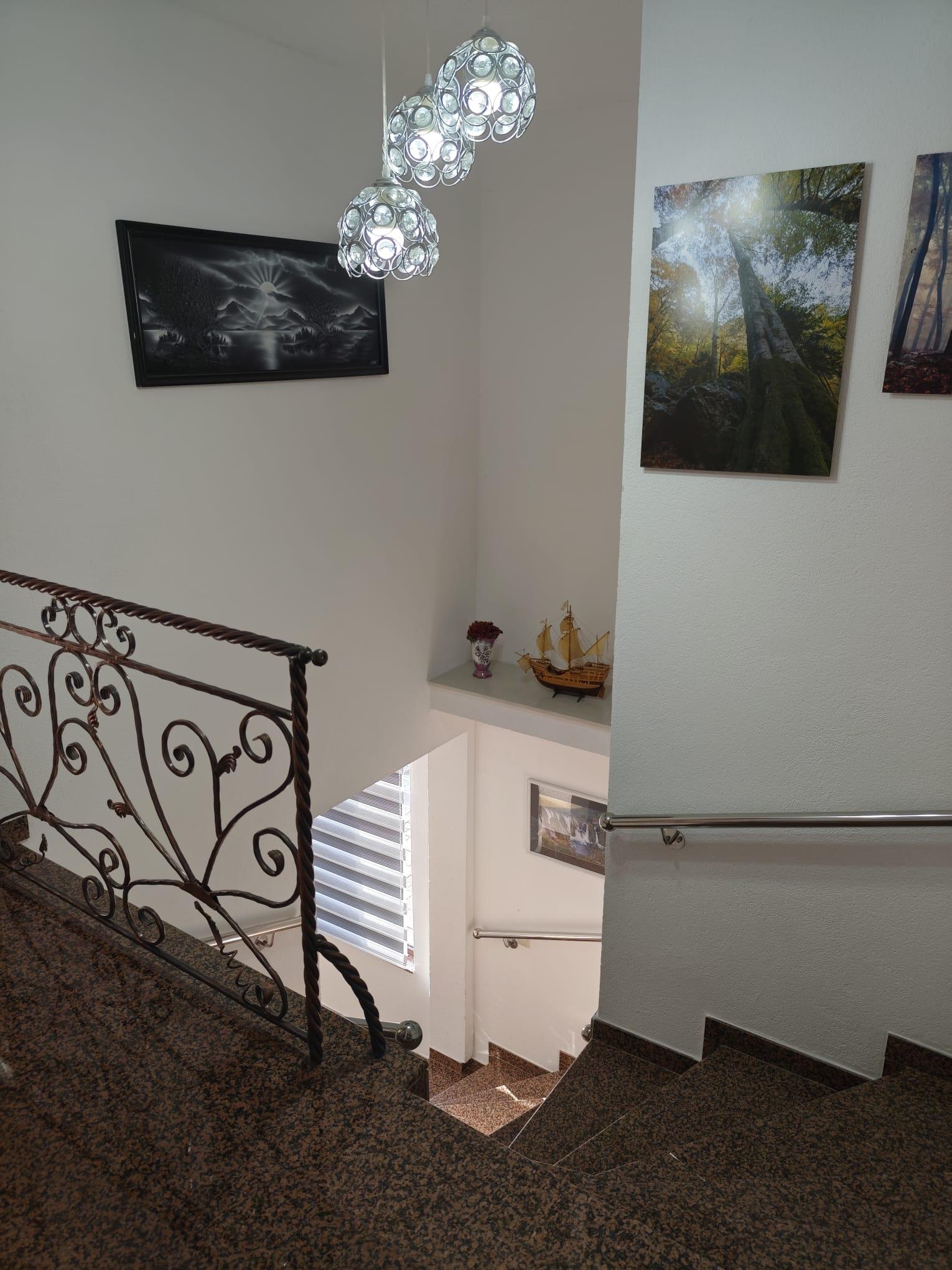 Odmorište stepeništa s ukrasnom željeznom ogradom, visećim svjetiljkama i slikama.
