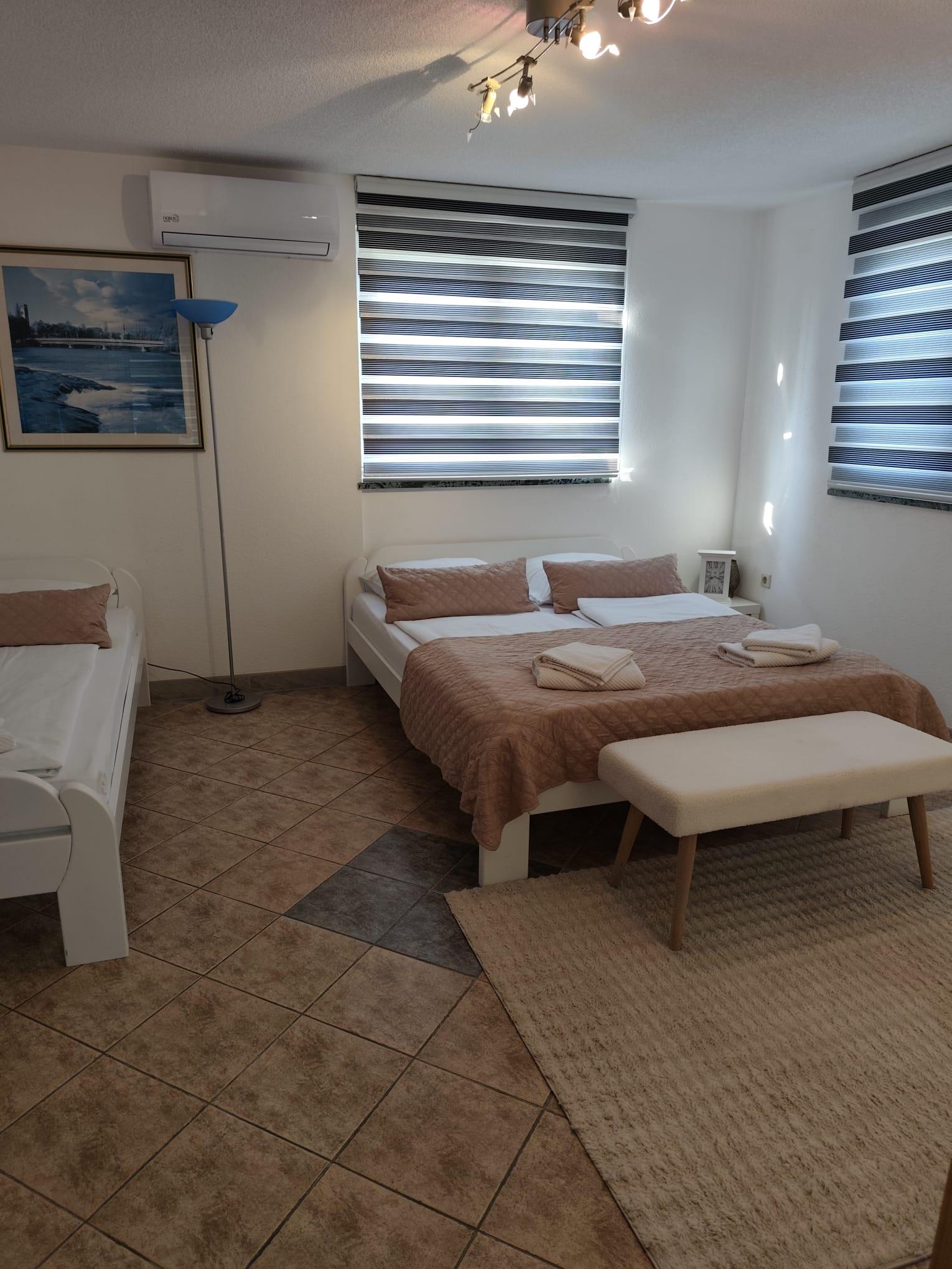 Schlafzimmer mit Doppelbett, Einzelbett und wandmontierter Klimaanlage.
