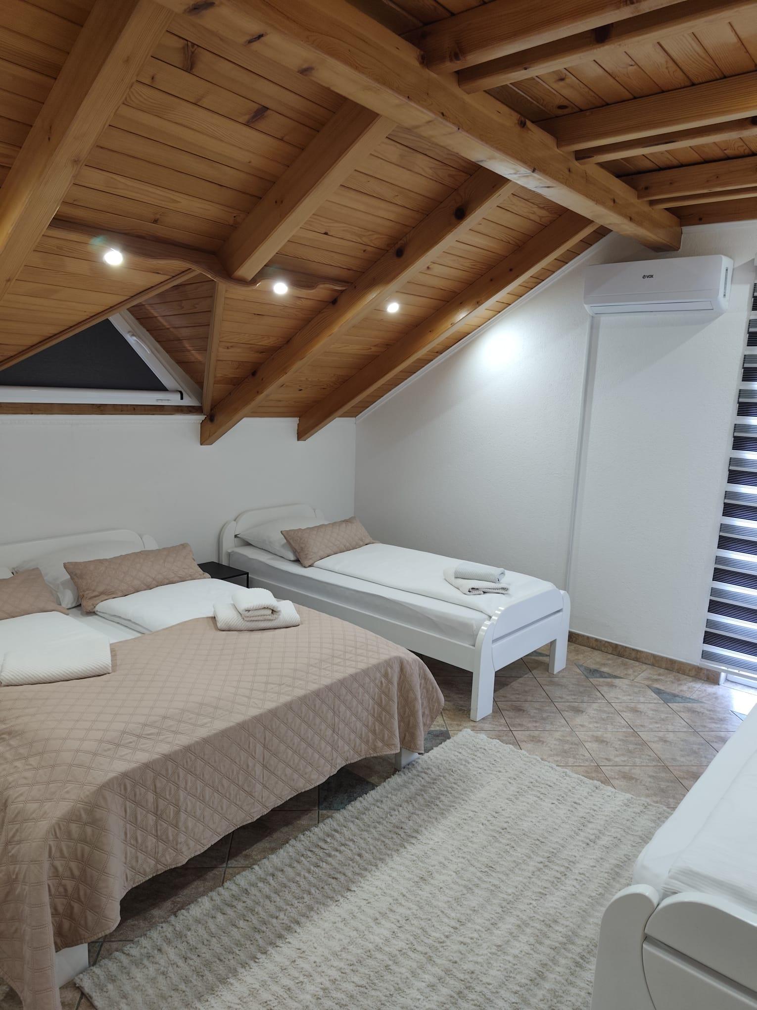 Schlafzimmer im Dachgeschoss mit Doppelbett, Einzelbett, Holzdecke und Klimaanlage.